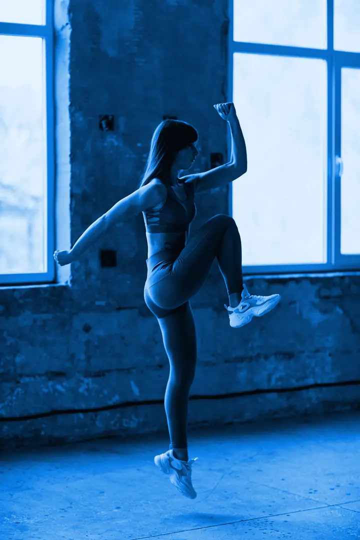 Mujer saltando con la rodilla arriba en una clase