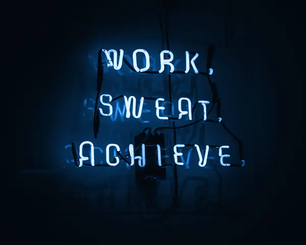 Cartel de neón que dice work, sweat, achieve